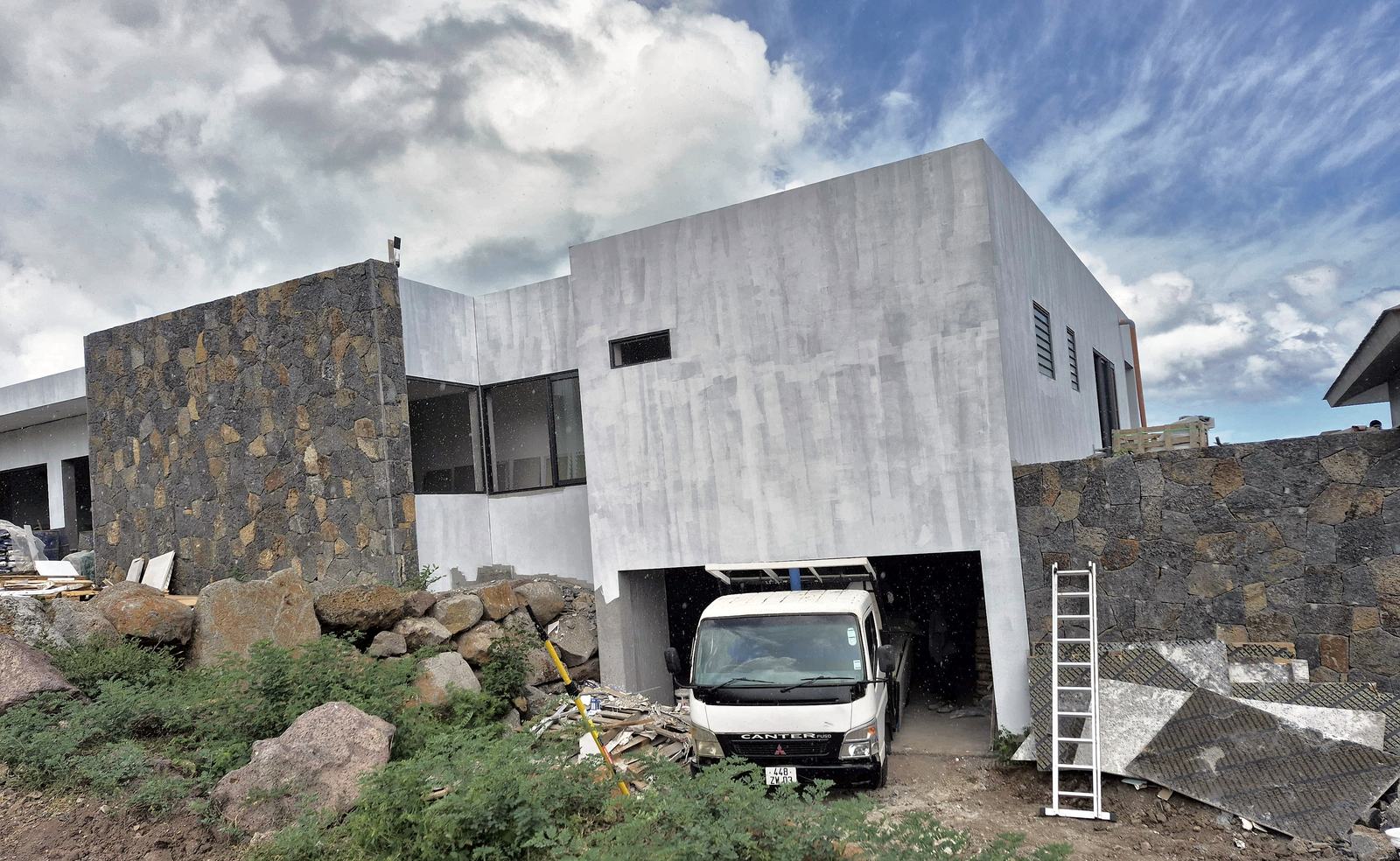 Villa contemporaine en cours de finition, façade enduite et murs en pierre de basalte